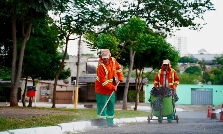 Imagem ilustrativa: Dois agentes da Comurg ( Companhia de Urbanização de Goiânia) realizando serviços de limpeza urbana em uma rua.