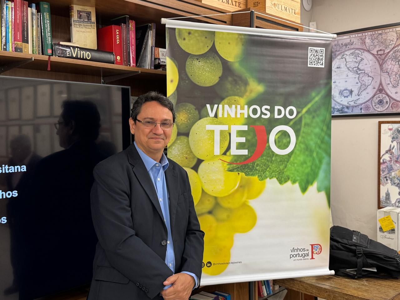 Imagem ilustrativa de Marcelo Copello ao lado de um banner de divulgação com a escrita "Vinhos do Tejo"