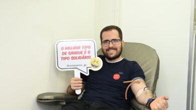 Imagem ilustrativa de um homem realizando uma doação de sangue e segurando uma placa com a escrita "O melhor tipo de sangue é o tipo solidário."